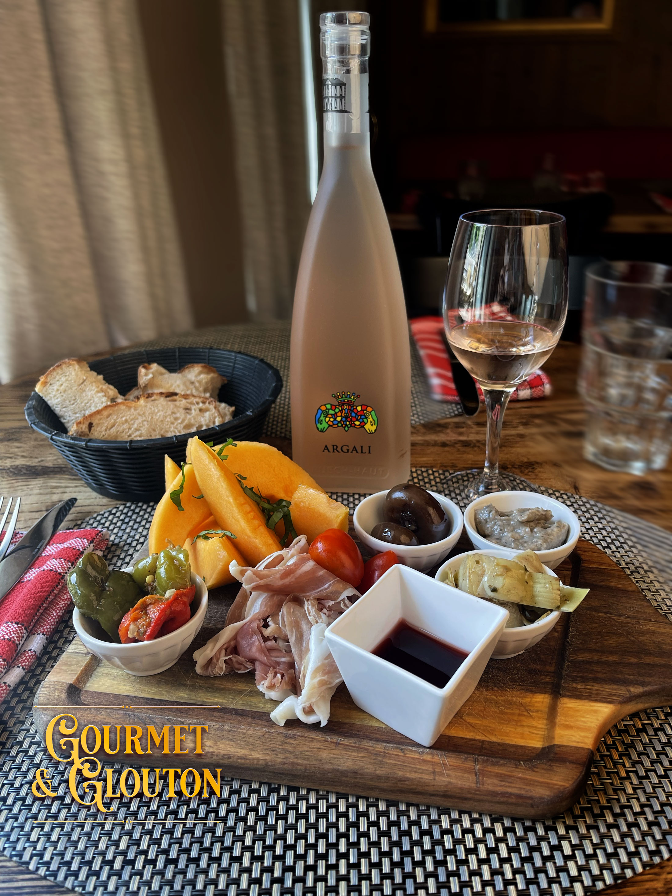 Dégustez une assiette estivale aux saveurs italiennes chez Gourmet & Glouton à Chaudes-Aigues : melon, jambon de pays, légumes marinés & vin rosé Argali en terrasse.