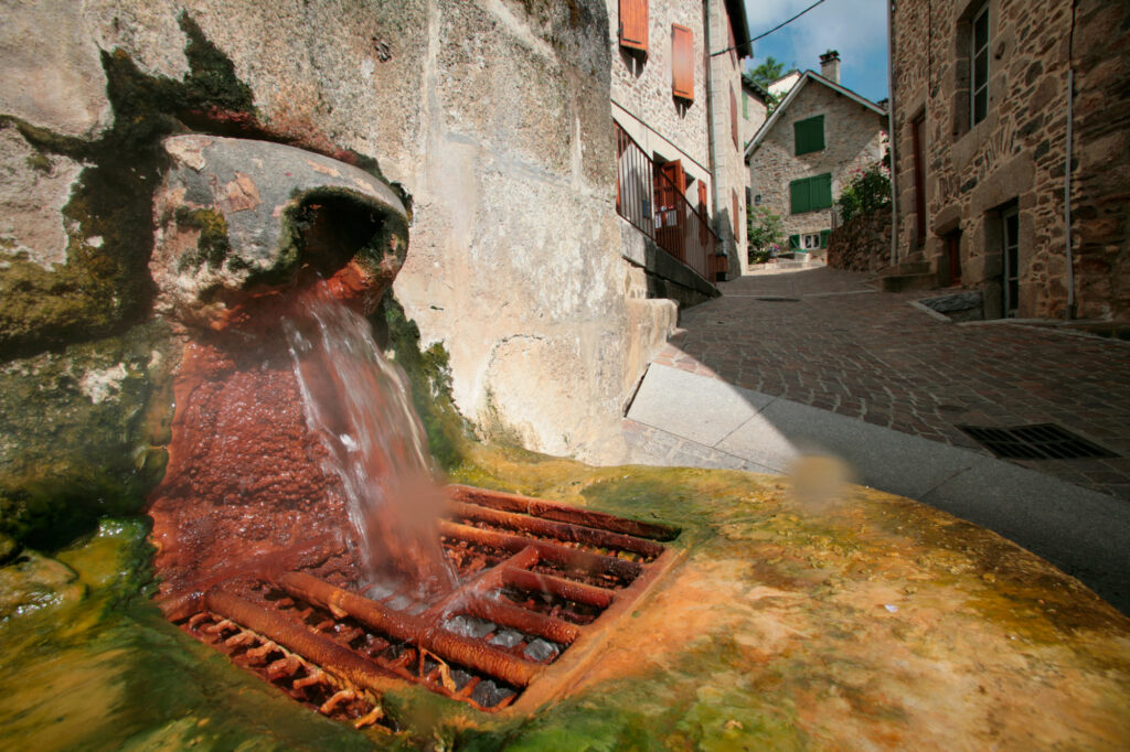 Source d’eau ferrugineuse à Chaudes-Aigues dans le Cantal avec dépôts de fer rouge caractéristiques