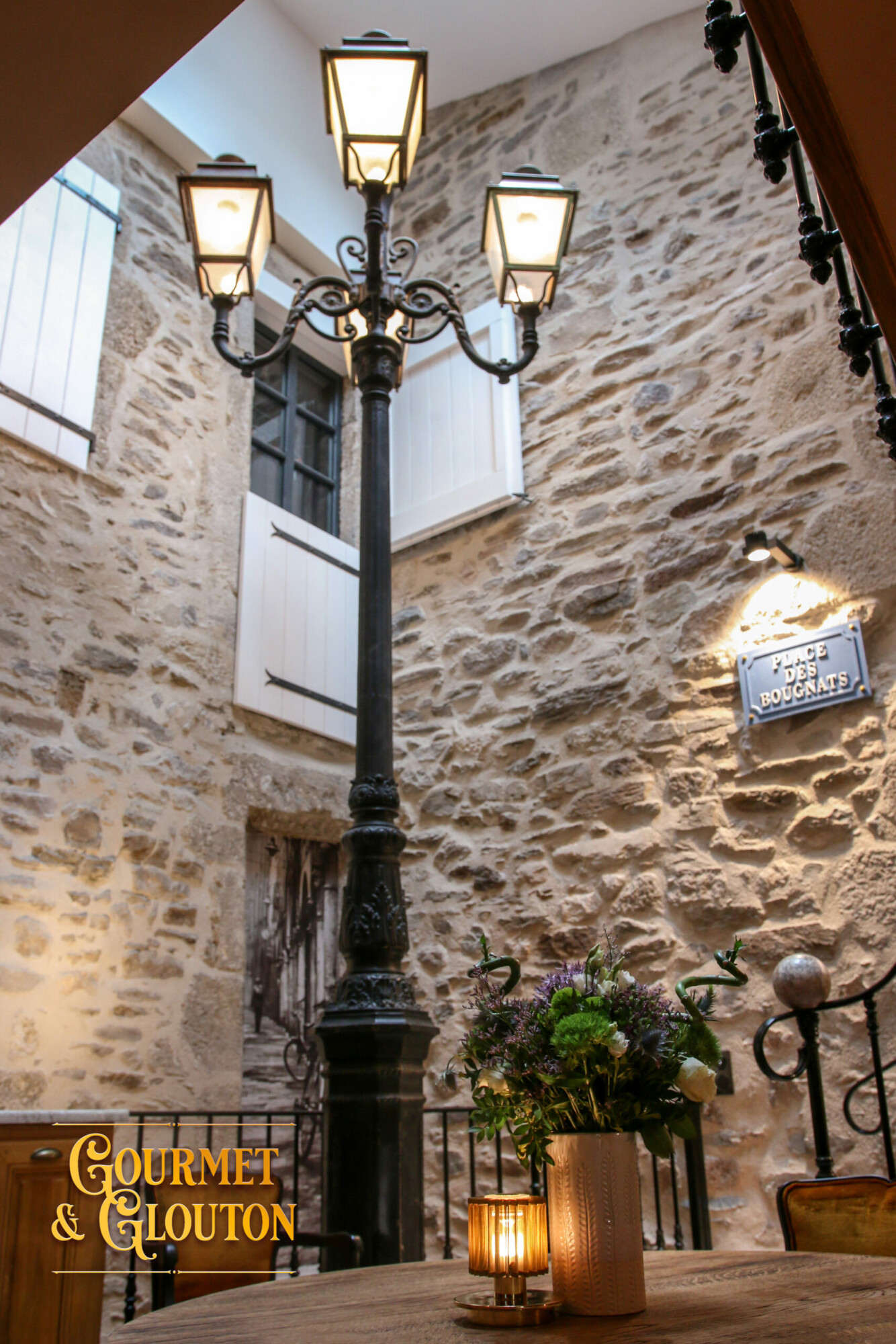 Réverbère du patio intérieur de Gourmet & Glouton à Chaudes-Aigues, ambiance chaleureuse en pierre et lumière douce.