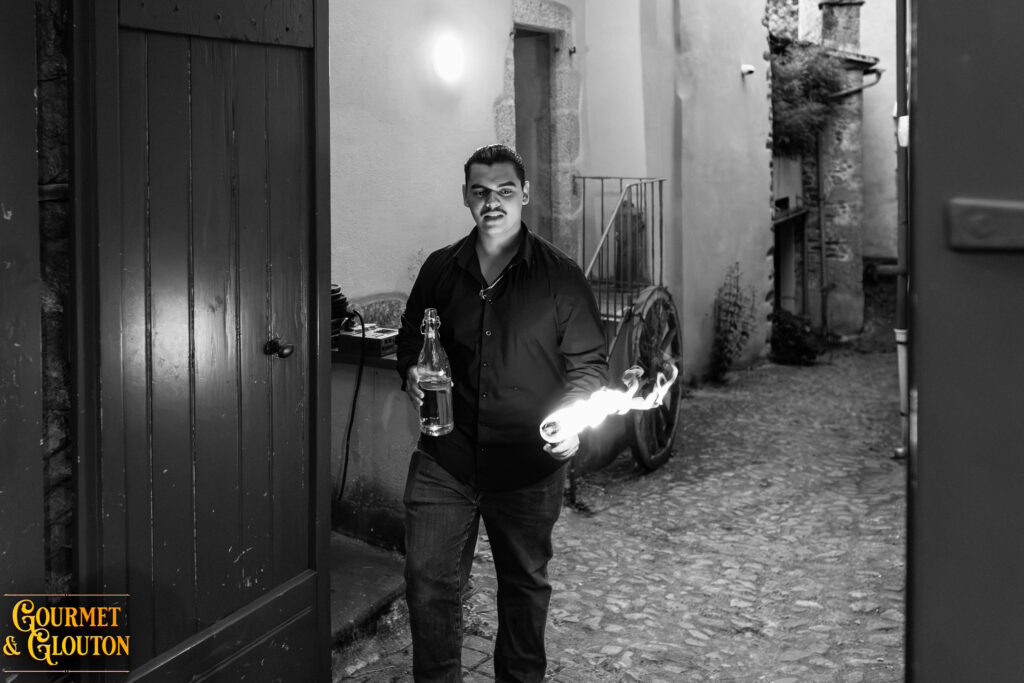 Enzo, alias Petit Dragon, capitaine de cuisine de Gourmet & Glouton, tenant une torche enflammée pendant les Terrasses Musicales à Chaudes-Aigues.