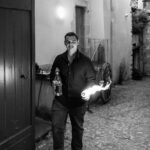 Enzo, alias Petit Dragon, capitaine de cuisine de Gourmet & Glouton, tient une torche enflammée pendant les Terrasses Musicales à Chaudes-Aigues.
