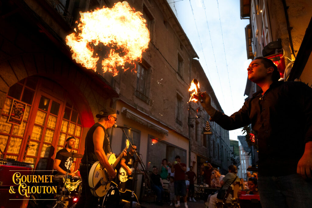 Petit Dragon, capitaine de cuisine de Gourmet & Glouton, réalise une animation de feu pendant le concert de Cadillac Rumble rue Notre-Dame d’Août à Chaudes-Aigues.
