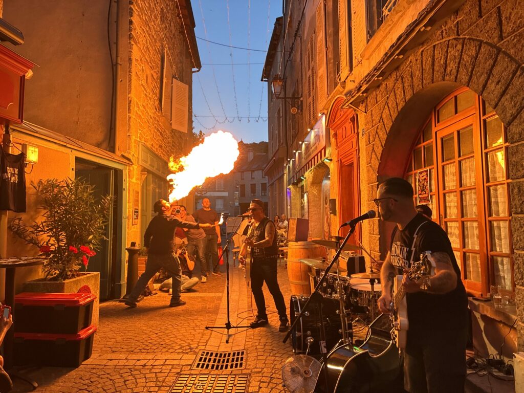 Petit Dragon, capitaine de cuisine de Gourmet & Glouton, crache le feu pendant le concert de Cadillac Rumble dans la rue Notre-Dame d’Août à Chaudes-Aigues.