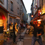 Petit Dragon réalise une animation de feu pendant le concert de Cadillac Rumble dans la rue Notre-Dame d’Août à Chaudes-Aigues.