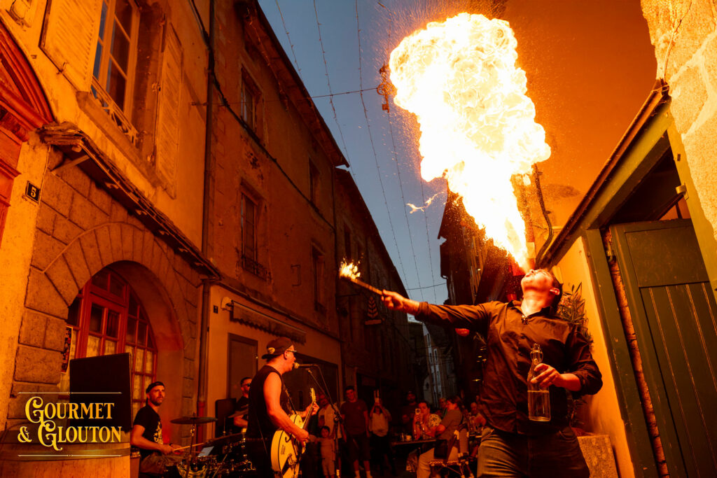 Petit Dragon, capitaine de cuisine de Gourmet & Glouton, crache le feu pendant une soirée des Terrasses Musicales à Chaudes-Aigues.