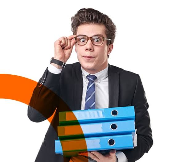 Homme en costume ajustant ses lunettes et tenant trois classeurs bleus sur fond blanc.